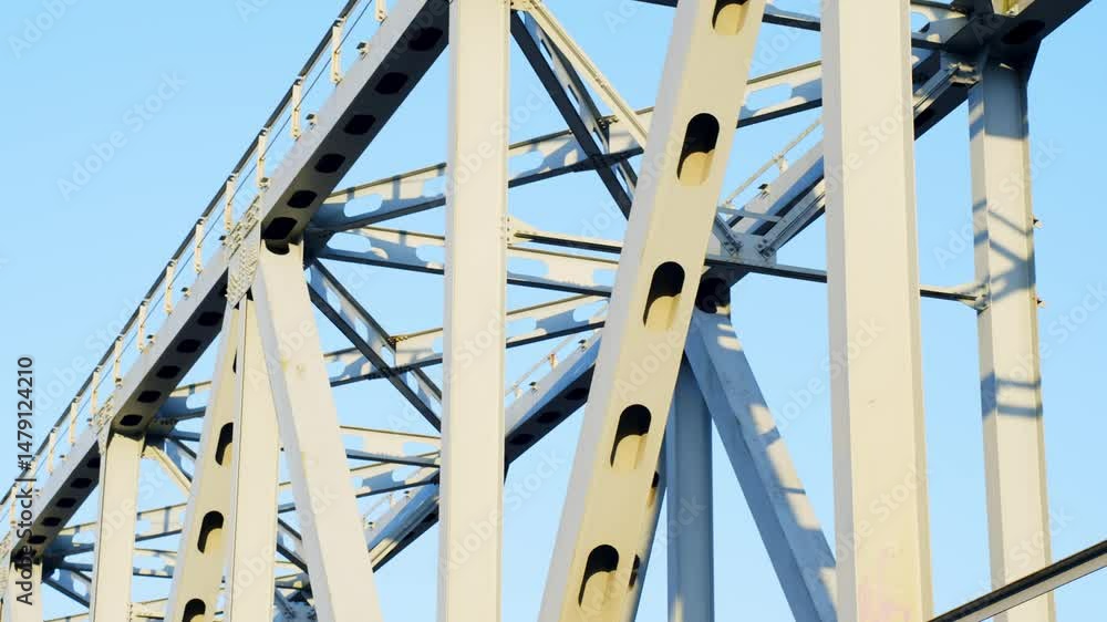 Steel bridge structure with rivets and beams under bright blue sky, for train crossing