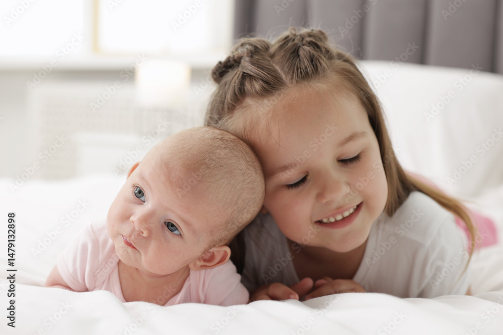 Cute girl and her little sister on bed at home Cute girl and her little sister on bed at home