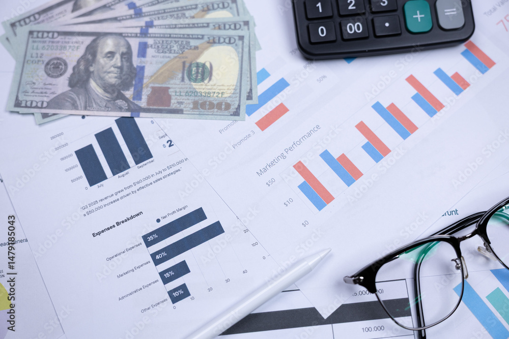 Obraz premium Financial charts, cash, calculator, and glasses on a desk, representing business analysis and financial planning.