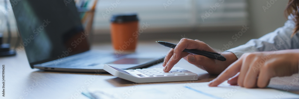 Fototapeta premium Accountant calculating finance with calculator and laptop in office