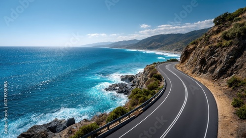 Fototapeta Naklejka Na Ścianę i Meble -  An empty asphalt road running along the edge of a rugged coastline