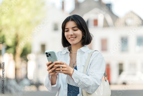 Waiting for directions to load, a stylish young woman of mixed heritage scrolls her phone against a charming European backdrop