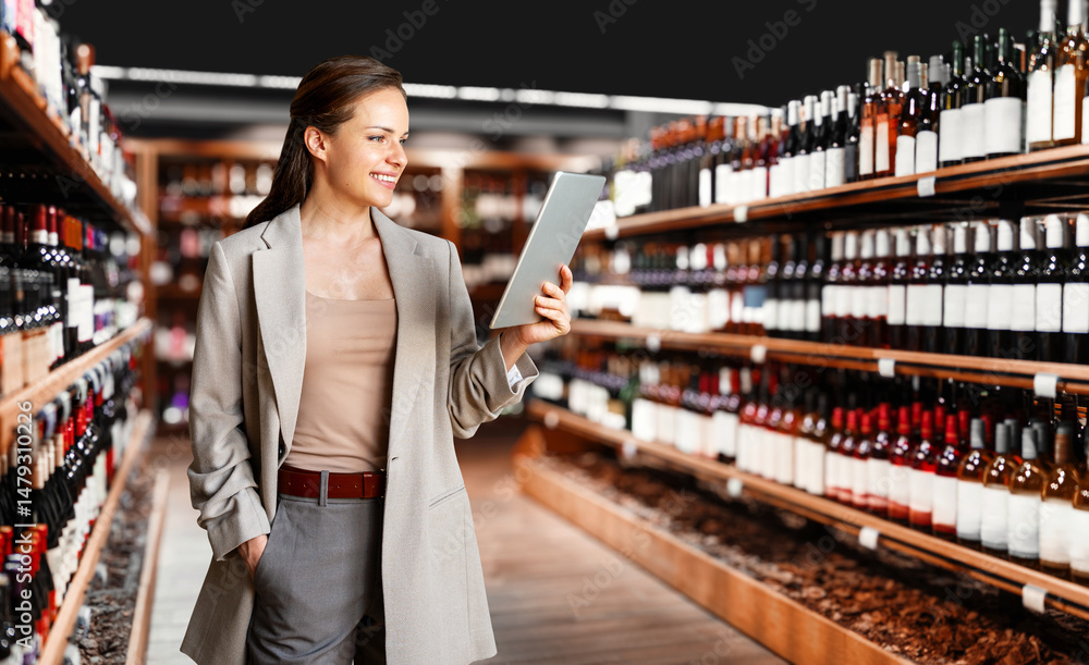 Confident businesswoman using digital tablet to manage liquor store and analyze retail KPI Confident businesswoman using digital tablet to manage liquor store and analyze retail KPI