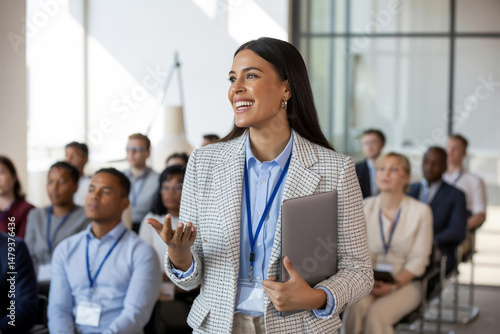 Smiling Hispanic Woman Giving Lecture To Audience Holding Laptop Business Event