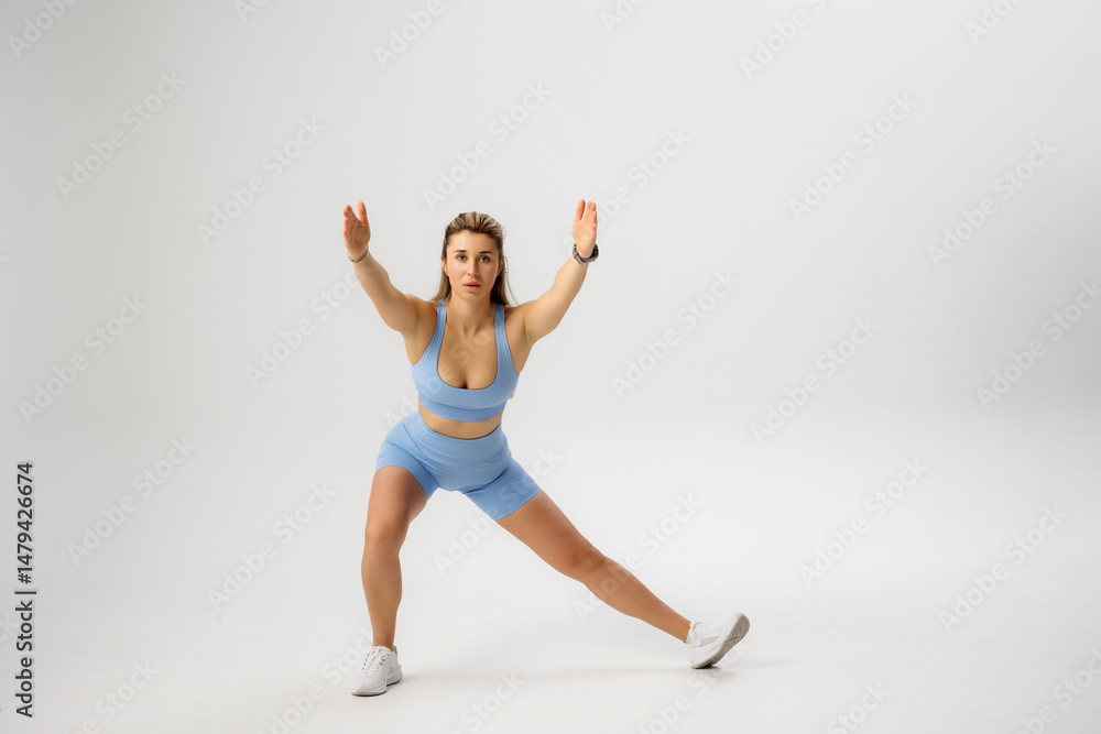 Fototapeta premium Fitness model performing a dynamic side lunge exercise in a studio setting during a fitness session