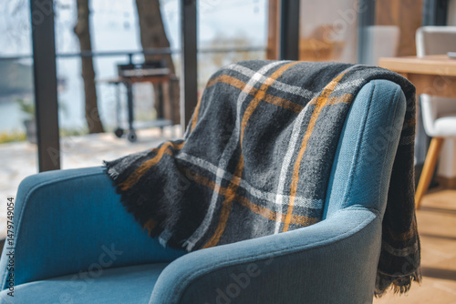 Fototapeta A plaid blanket draped over a blue chair