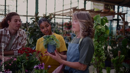 Wallpaper Mural Green themed greenhouse interior featuring experienced gardener guiding young couple through plant selection, offering detailed care advice and professional horticultural consultation Torontodigital.ca