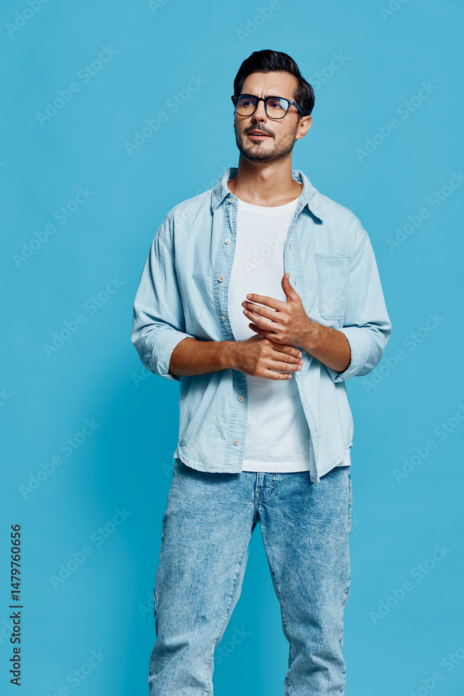 Full body smiling man wearing light denim shirt and eyeglasses, looking at the camera with a thoughtful expression, isolated on bright blue background. People lifestyle concept. Full body smiling man wearing light denim shirt and eyeglasses, looking at the camera with a thoughtful expression, isolated on bright blue background. People lifestyle concept.