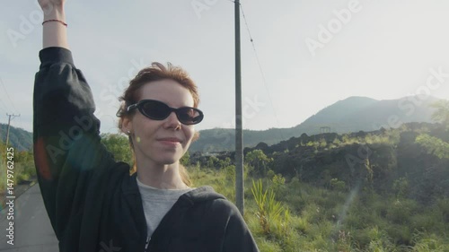 Happy tourist woman raising arm near mount batur in bali