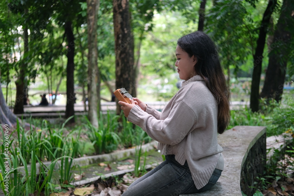 woman playing a kalimba in a vibrant park filled with green leaves on a warm summer day woman playing a kalimba in a vibrant park filled with green leaves on a warm summer day