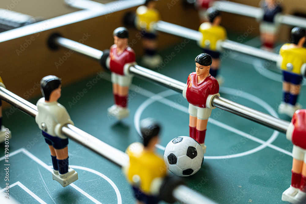 Fototapeta premium Detailed image of a foosball game in progress, focusing on the players and ball.