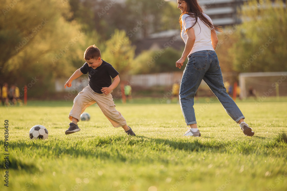 Obraz premium Active time spending with soccer ball. Mother and son are together on the summer field