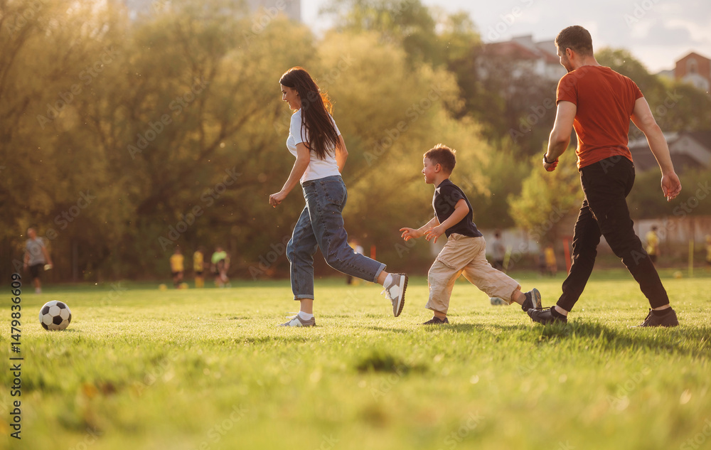 Obraz premium Soccer game. Family of mother, father and son are playing on the field