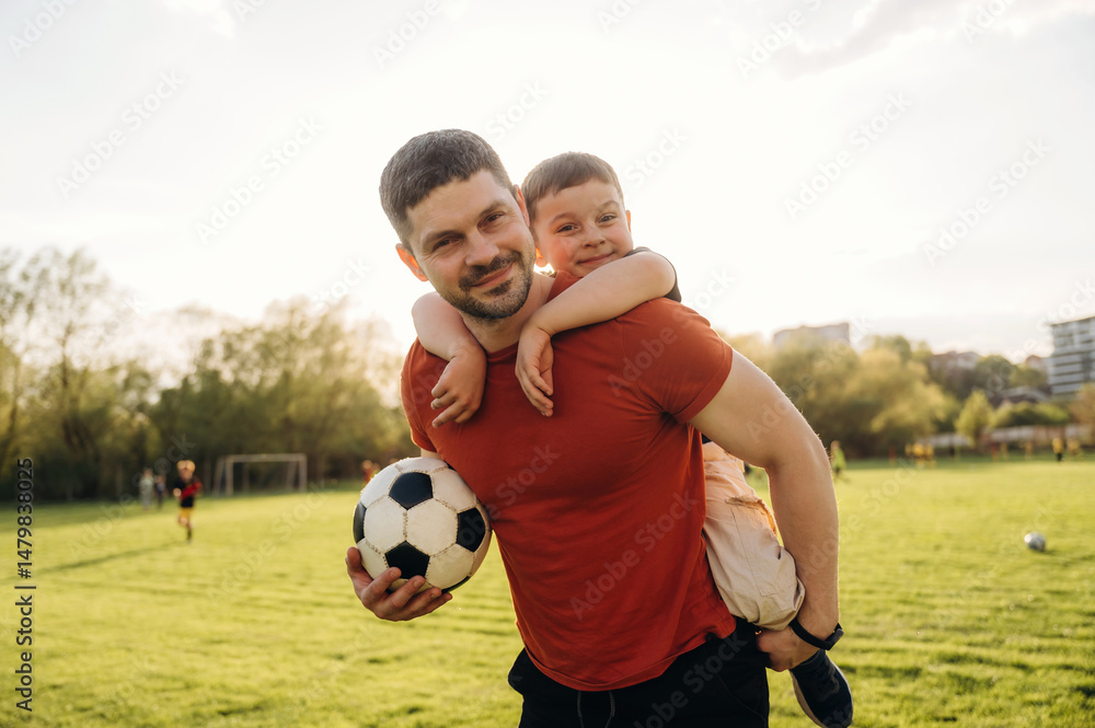 Obraz premium Ready to play soccer, boy is sitting. Father and son are having fun outdoors