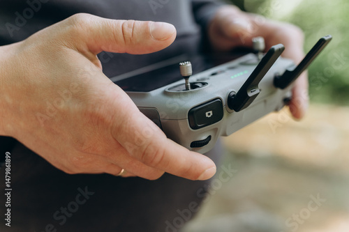 Close-up of hands holding and using a remote controller to operate a drone outdoors. Concept of modern technology, navigation and aerial photography.