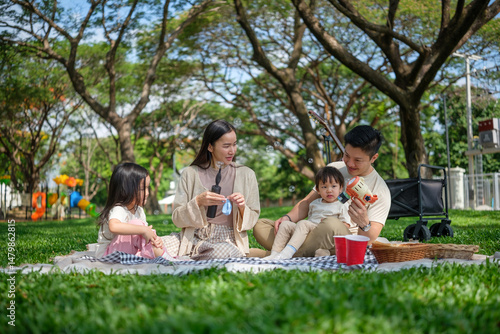 Family picnic under trees with bubble play and joyful moments captured in a serene green space.