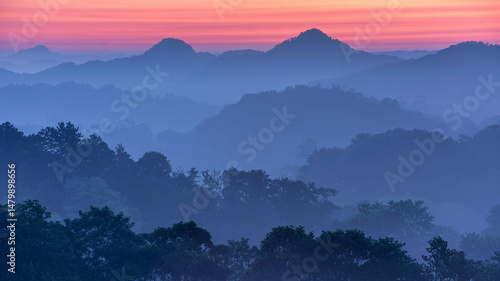 A misty sunrise paints the mountain landscape with beauty as the morning fog rolls through the valley
