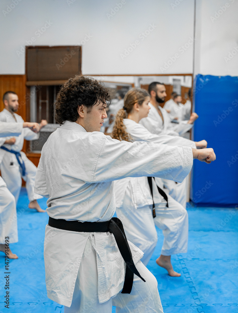 Fototapeta premium Young karate student practicing martial arts in dojo with group training