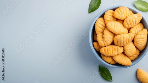 Delicious homemade potato gnocchi in a light blue bowl with fresh green leaves on a pastel background, Italian traditional soft pasta dish for lunch or dinner
