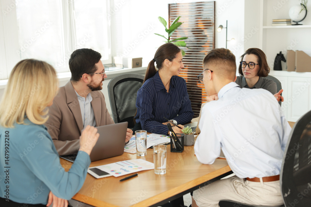Coworkers working together at wooden table in office Coworkers working together at wooden table in office