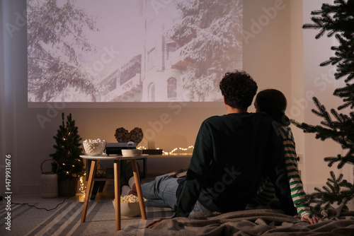 Tableau sur toile Couple watching Christmas movie via video projector at home, back view