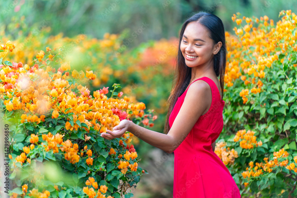 Naklejka premium Beauty shot of Asian woman in red dress immerse happily in a garden of blooming flowers