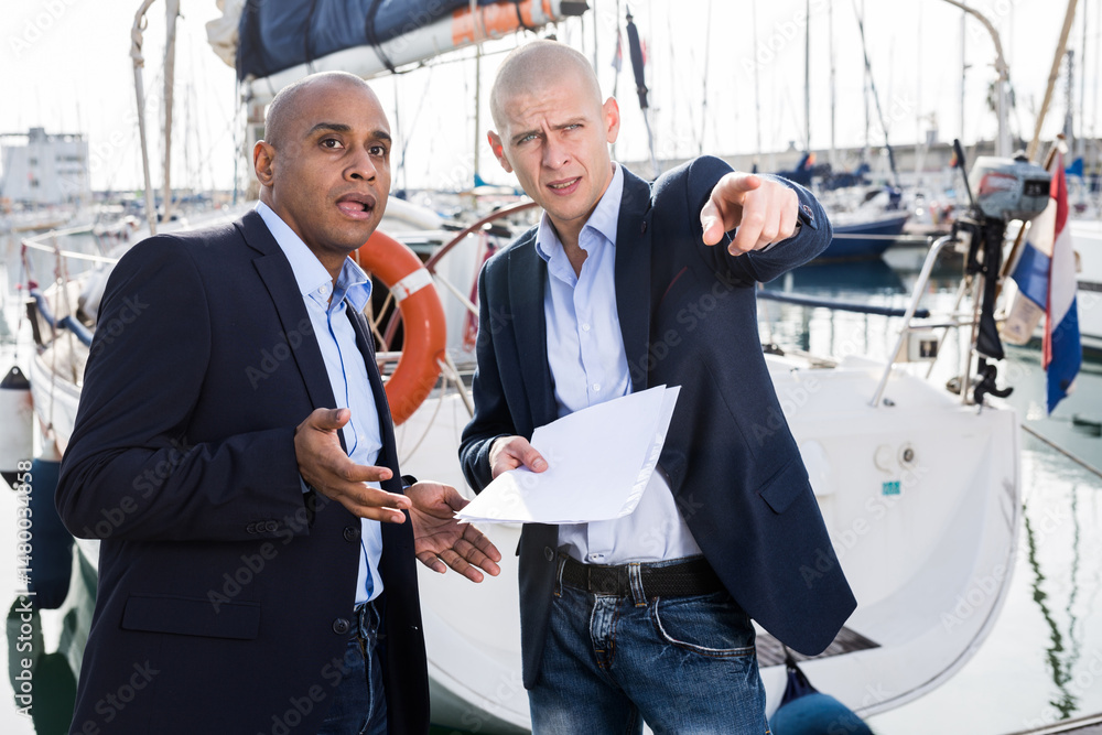 Two male businessmen choosing and buying a yacht at seaport