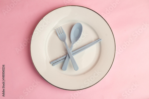 Minimalist style tableware, white round plate, gray spoon, fork and chopsticks made of plastic material, ping canvas background