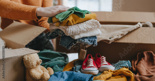 Photos Woman sorting an old out-of-use kid toy, clothes and shoes in box for charity or