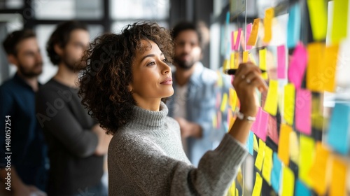 Women looking at sticky notes on office wall,creativity or inspiration during brainstorming session.