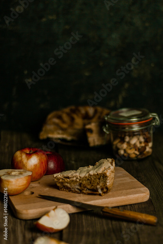 Traditional apple pie Charlotte apples are lying nearby. Sweet Thanksgiving dinner, autumn seasonal apple pie sliced one piece on wooden tray, on dark wooden background.