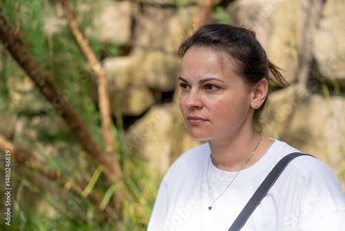 Serious woman in white t-shirt in summer outdoors. Focused look ahead