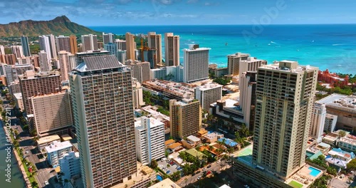 Flight around the high-rise building with solar panels on the top. Waterscape of the Pacific Ocean with boats and surfers on.