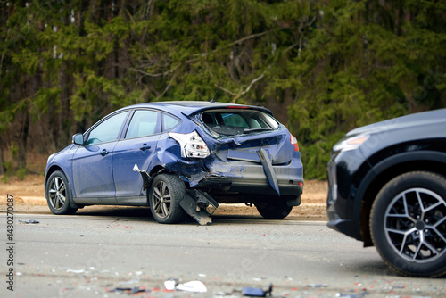 Valokuvatapetti Blue compact car with severe rear end damage after highway collision, debris scattered on the road and another vehicle visible at the scene of the traffic accident