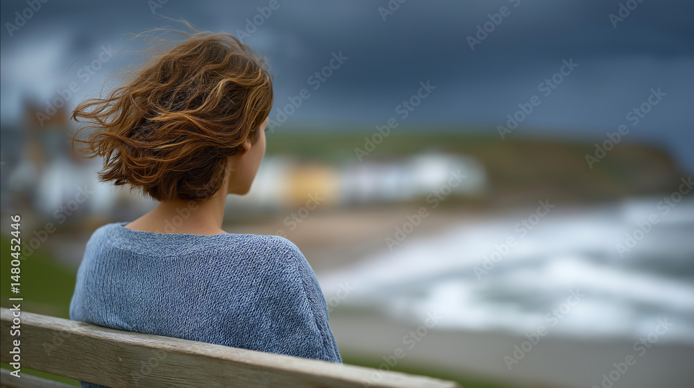 Fototapeta premium A woman gazes at the sea from a cliffside bench