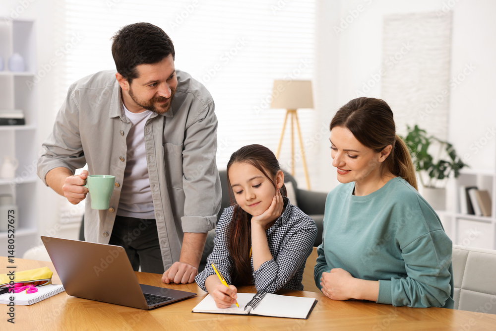 Parents helping their daughter with homework at wooden table indoors Parents helping their daughter with homework at wooden table indoors