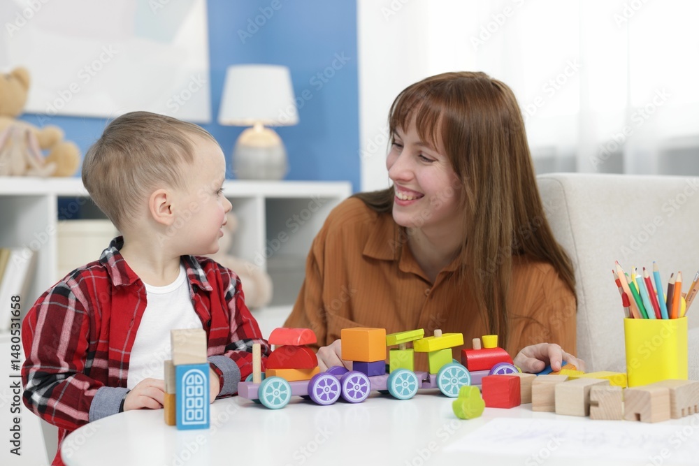 Fototapeta premium Mother and son playing with toys at table indoors