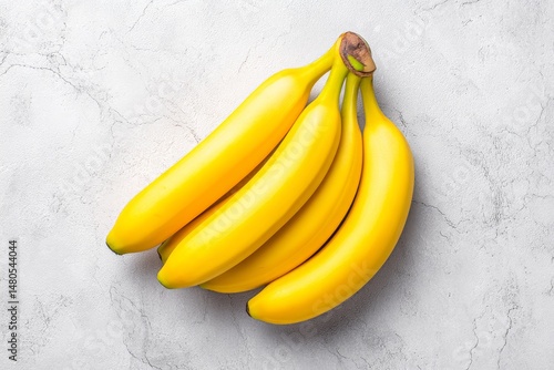 Fresh Yellow Bananas Bunch - A bunch of four ripe yellow bananas on a light gray marble background