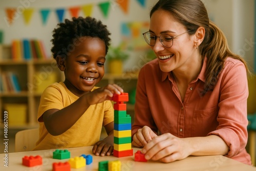 A black youngster and a specialist in child development are having fun building with bricks