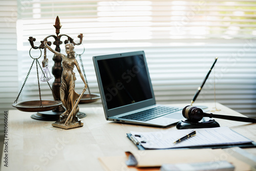 Lady Justice, scales, and a gavel placed on a judge’s desk represent fairness and integrity in law and courtroom proceedings.