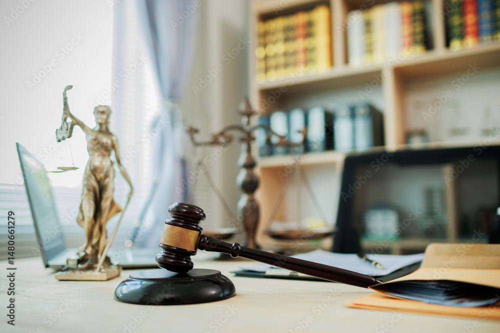 Lady Justice, scales, and a gavel placed on a judge’s desk represent fairness and integrity in law and courtroom proceedings.