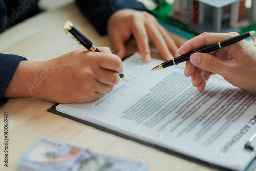 Obraz na płótnie A real estate agent and client sign a home purchase agreement, formalizing the sale and confirming terms of the property transaction. w salonie