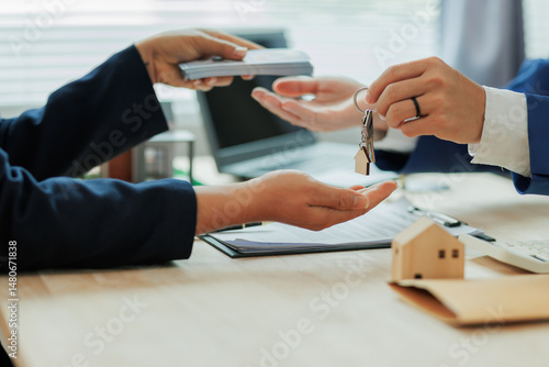 Obraz na płótnie Client pays the agent, who hands over the house keys, marking the official closing and completion of the real estate transaction. w salonie
