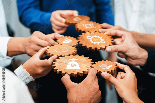A diverse group of individuals collaboratively holds wooden gears that symbolize teamwork and innovation, representing a modern approach to problem solving in business settings. Amity