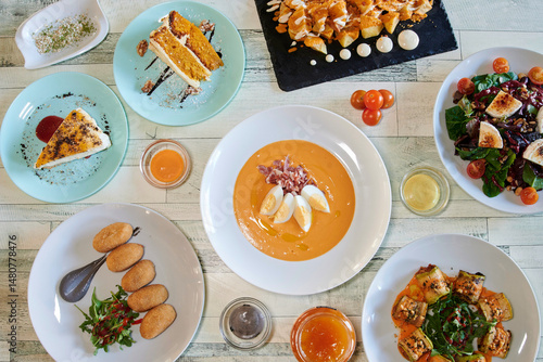 Wallpaper Mural A table with many plates of food, including a cake, a salad, and a soup. There are also some bowls and cups on the table Torontodigital.ca