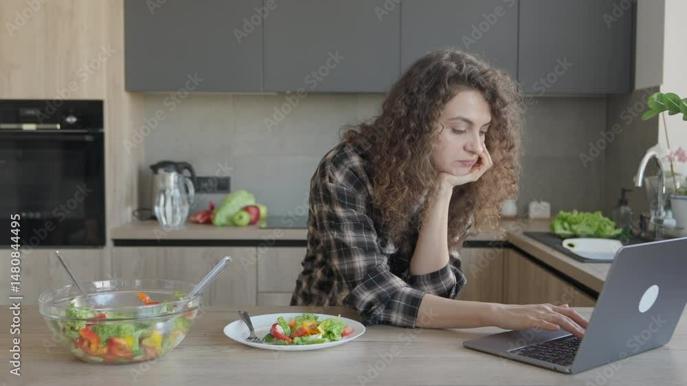 Focused Woman Working On Laptop While Having Healthy Lunch In Cozy Kitchen Focused Woman Working On Laptop While Having Healthy Lunch In Cozy Kitchen