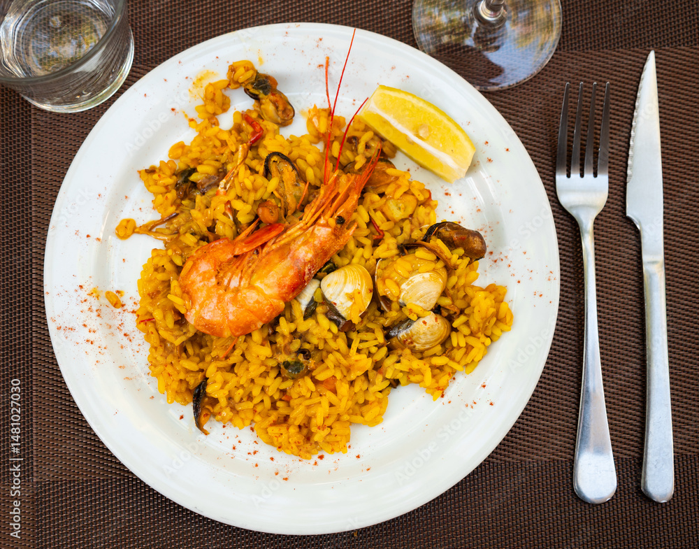 Paella made of rice and different seafood served in plate with other table appointments