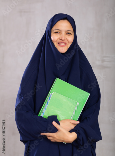 Portrait of young woman student in a khimara with notebooks in her hands