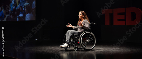 Woman in wheelchair speaking on TED stage