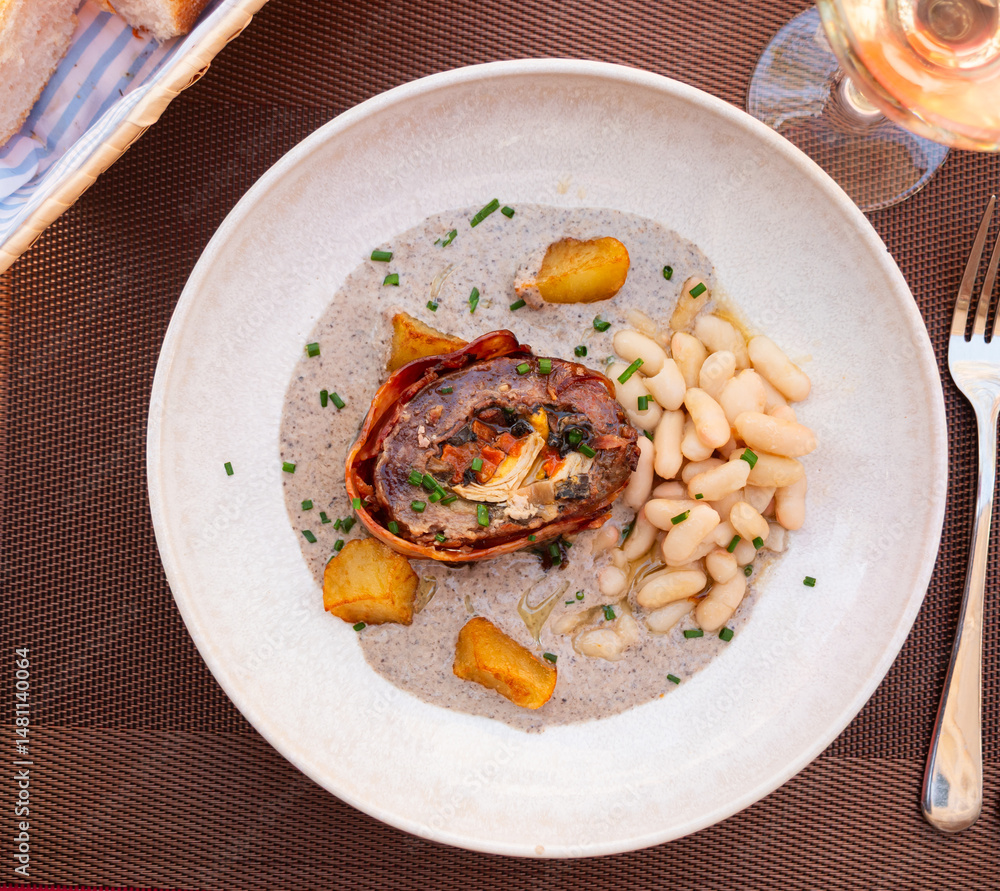 Delicious meatloaf served with beans and potatoes in sauce on plate